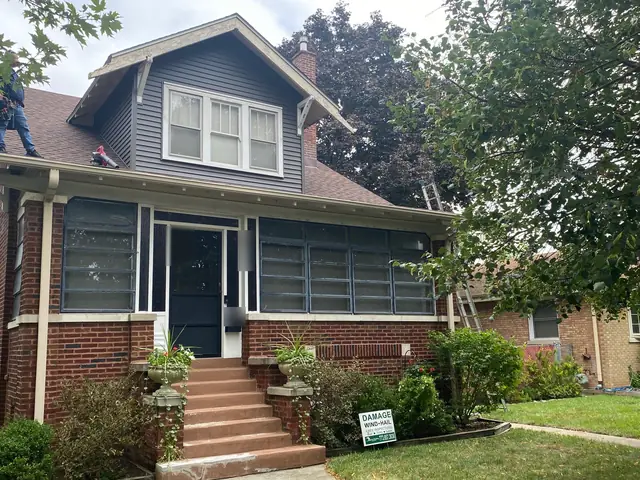 Brick bungalow with a new shingle roof and its dormer re-sided in dark gray