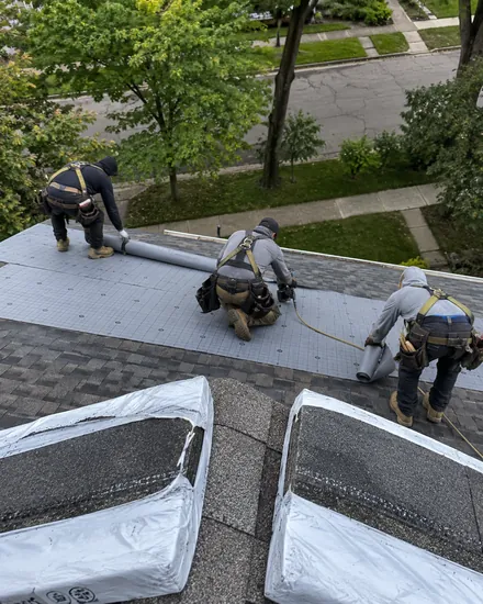 Roofers rolling out underlayment on a pitched shingle roof